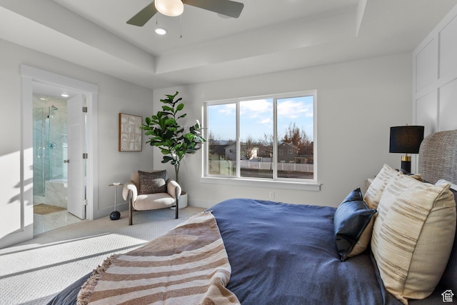 carpeted bedroom with ensuite bathroom, recessed lighting, baseboards, a tray ceiling, and ceiling fan