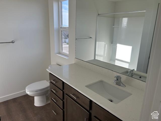 bathroom with baseboards, toilet, vanity, and wood finished floors
