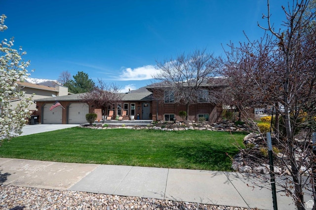 split level home featuring a front lawn, an attached garage, driveway, and brick siding