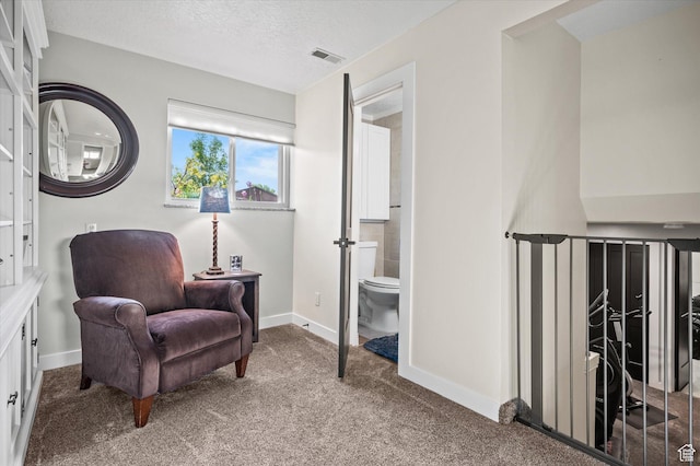 living area featuring baseboards, carpet, and a textured ceiling