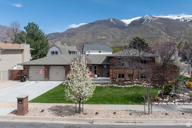 tri-level home with a garage, driveway, a mountain view, brick siding, and a shingled roof