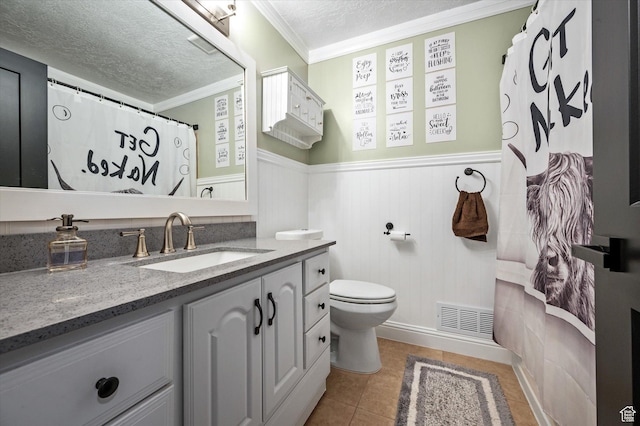 bathroom with a textured ceiling, a wainscoted wall, vanity, ornamental molding, and toilet