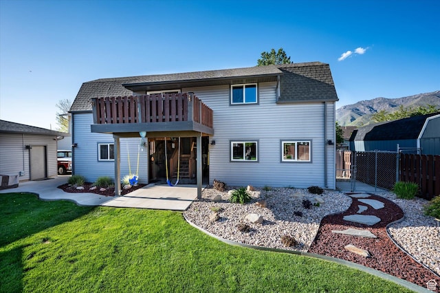 back of house featuring roof with shingles, a mountain view, and a patio area