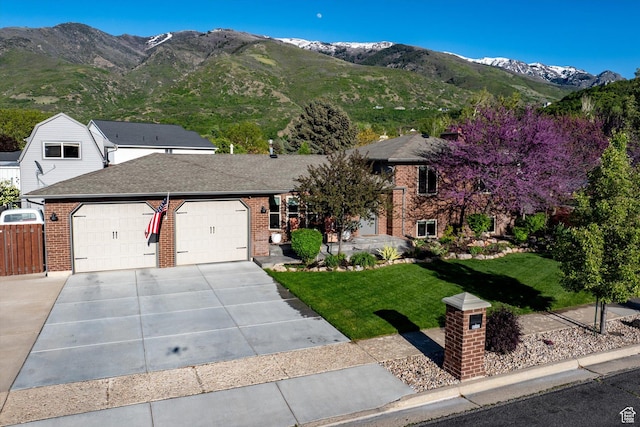 view of front of house featuring brick siding, an attached garage, concrete driveway, and a mountain view