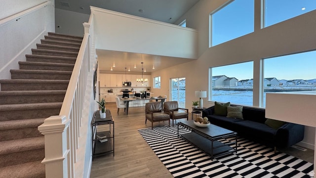 living room featuring light wood-style floors, stairway, a high ceiling, and a chandelier