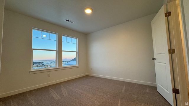unfurnished room featuring baseboards and dark carpet