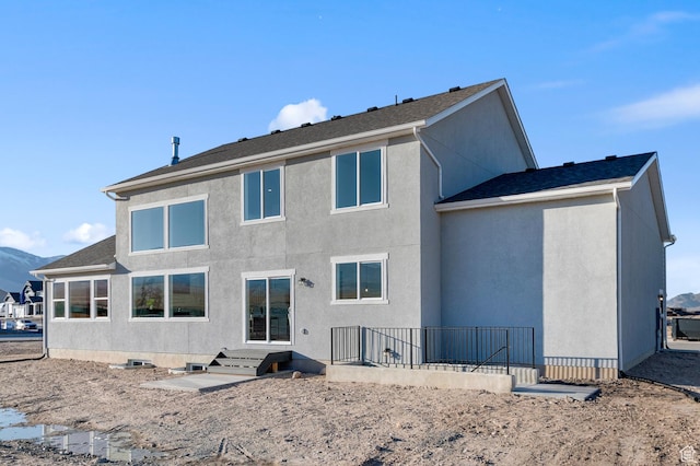 rear view of house featuring stucco siding and a mountain view