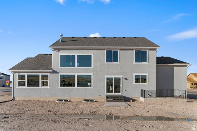 back of property with a shingled roof and stucco siding