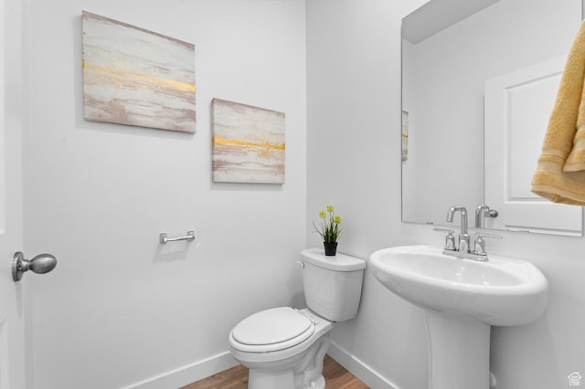 bathroom featuring baseboards, wood finished floors, and toilet