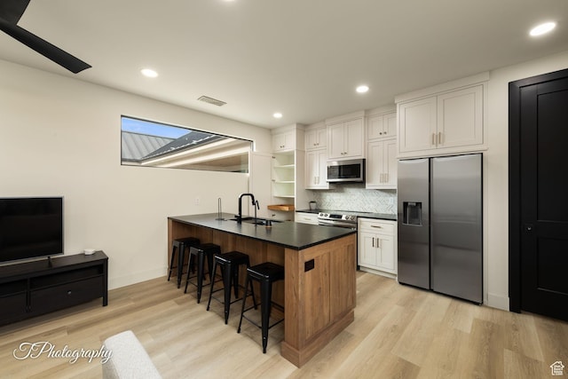 3195 S Tallow Tree Dr, St George, UT 84790 - kitchen with stainless steel appliances, a kitchen bar, dark countertops, a peninsula, and white cabinetry