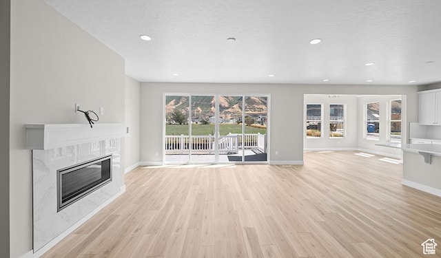 unfurnished living room featuring a fireplace, baseboards, light wood-type flooring, and recessed lighting