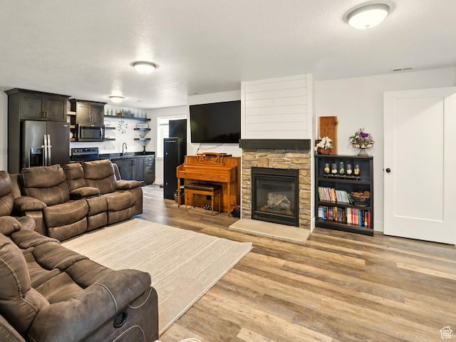114 E 9500 S, Paradise, UT 84328 - living area with bar with sink, light wood-style flooring, a fireplace, and a textured ceiling