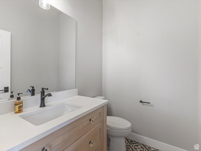 half bath featuring toilet, vanity, and baseboards