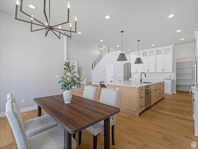 dining area with recessed lighting, light wood finished floors, baseboards, a chandelier, and arched walkways