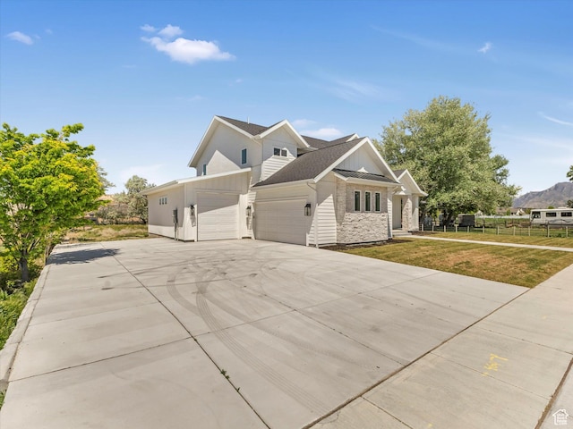 view of side of property featuring an attached garage, board and batten siding, stone siding, a yard, and concrete driveway