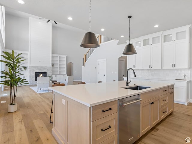 kitchen featuring a sink, stainless steel dishwasher, arched walkways, light wood finished floors, and recessed lighting