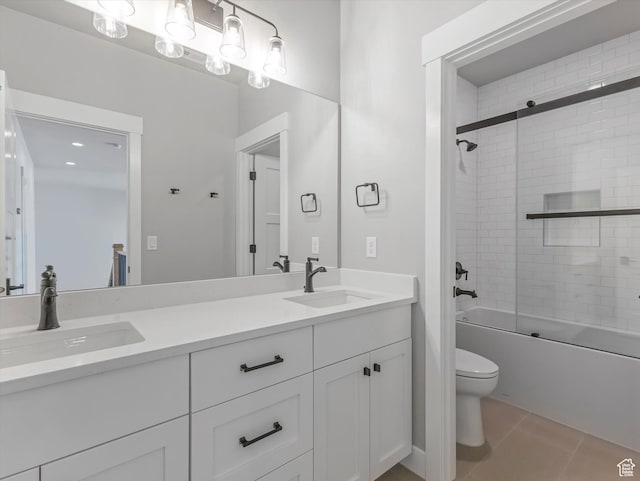 bathroom featuring toilet, double vanity, bath / shower combo with glass door, and tile patterned flooring