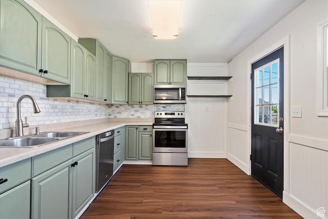 kitchen with green cabinetry, appliances with stainless steel finishes, a sink, and decorative backsplash