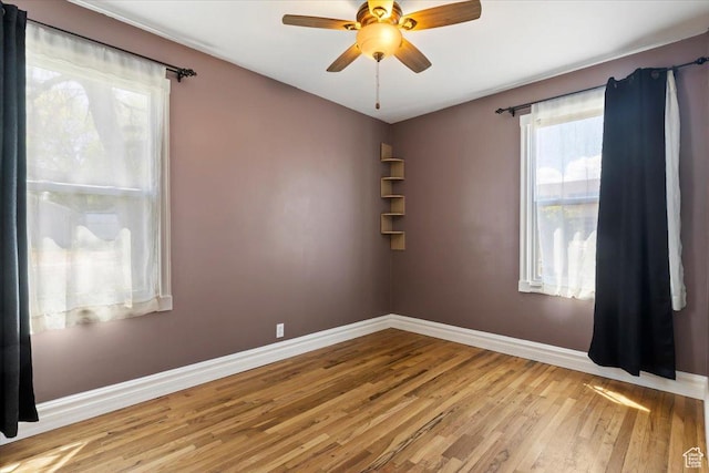 unfurnished room featuring wood finished floors, baseboards, and ceiling fan