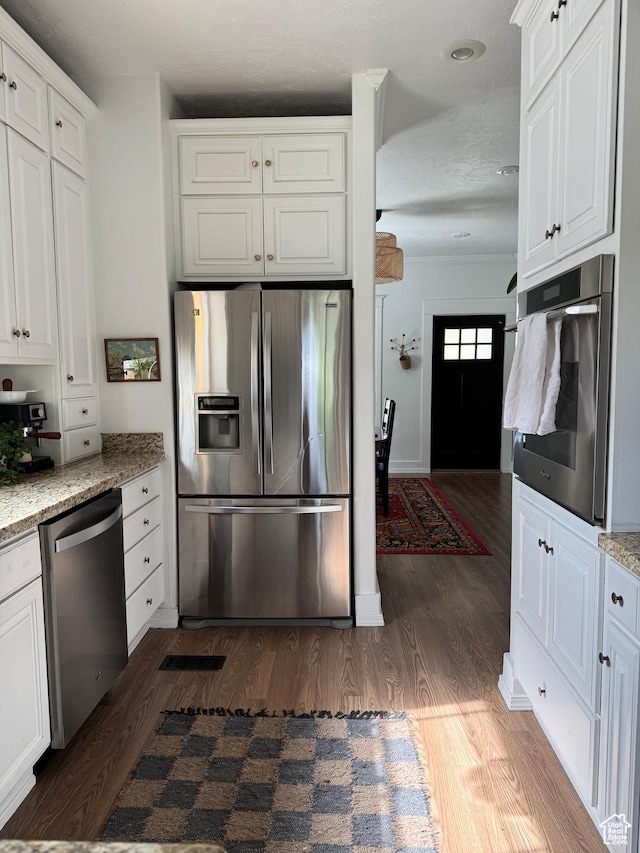 kitchen featuring stainless steel appliances, dark wood finished floors, white cabinets, and light stone counters