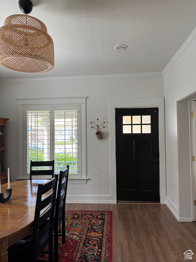 entrance foyer with wood finished floors, ornamental molding, baseboards, and a textured ceiling