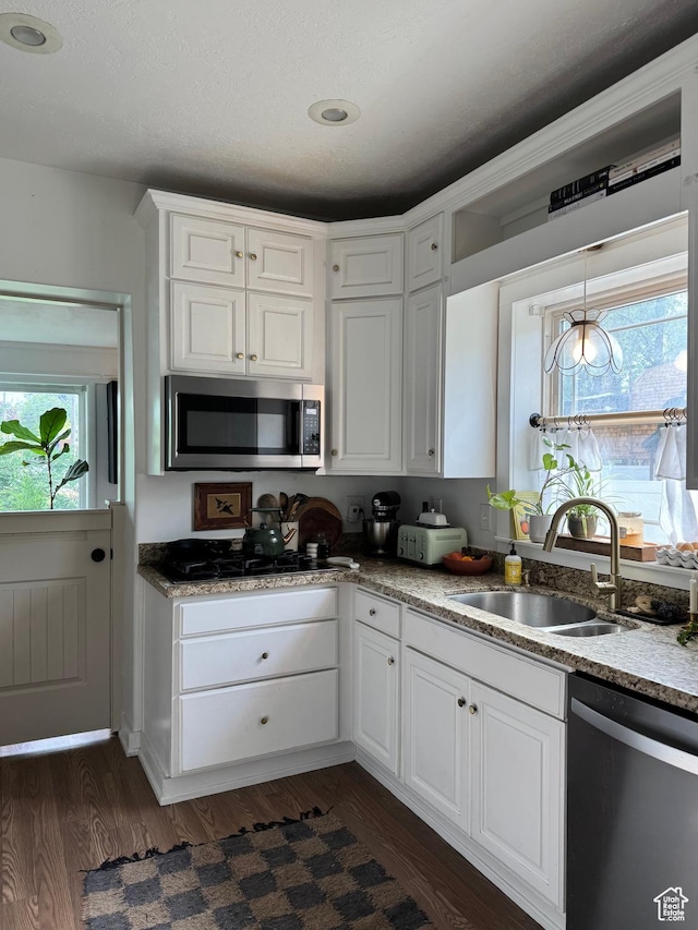 kitchen featuring appliances with stainless steel finishes, a sink, white cabinets, and healthy amount of natural light