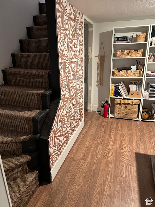 staircase featuring wood finished floors and baseboards