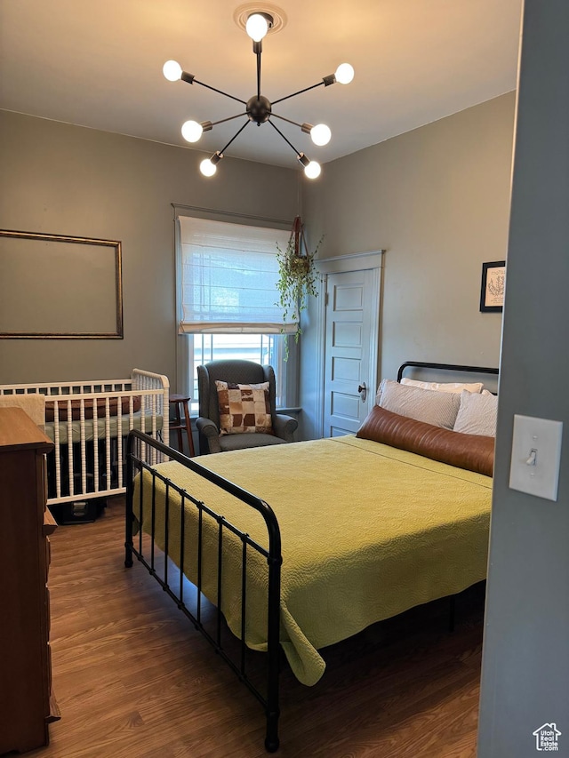 bedroom with wood finished floors and a chandelier