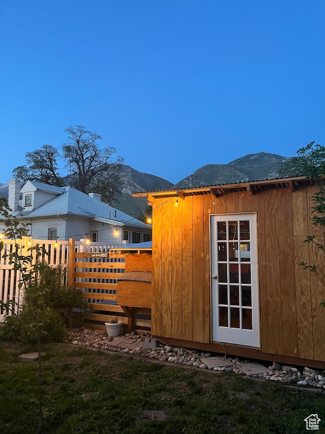 view of outdoor structure with fence, a mountain view, and an outdoor structure