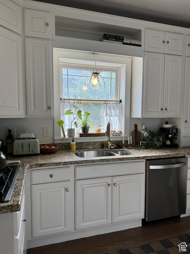 kitchen featuring appliances with stainless steel finishes, a sink, white cabinets, pendant lighting, and dark wood-type flooring