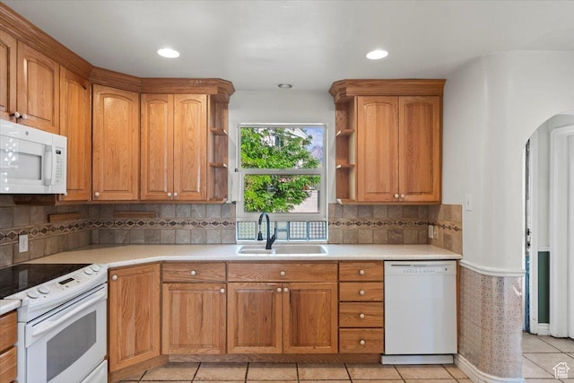kitchen with white appliances, a sink, open shelves, light countertops, and arched walkways