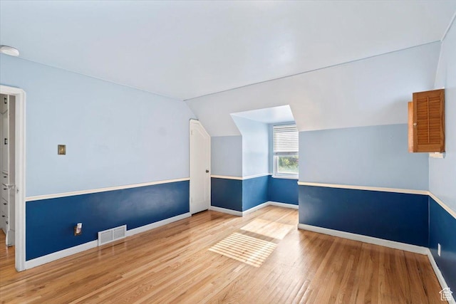 additional living space featuring wood finished floors, lofted ceiling, and baseboards