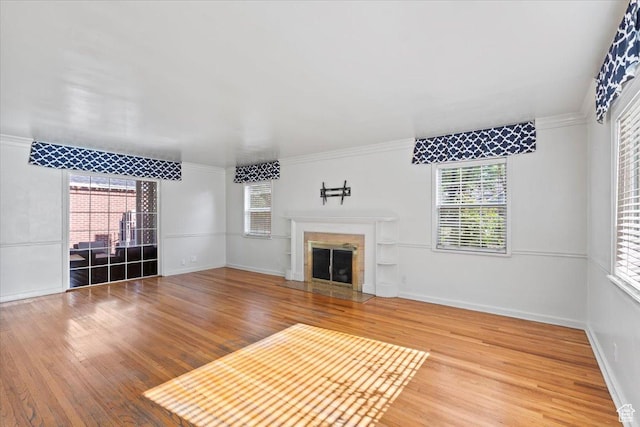 unfurnished living room with wood finished floors, a fireplace, ornamental molding, and baseboards