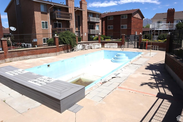 community pool with fence and a patio area