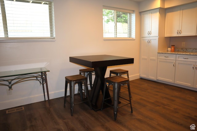 dining area with dark wood-style flooring and baseboards