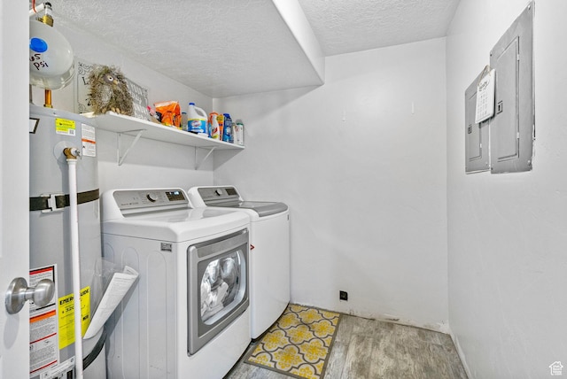 laundry room featuring water heater, washing machine and clothes dryer, a textured ceiling, and electric panel