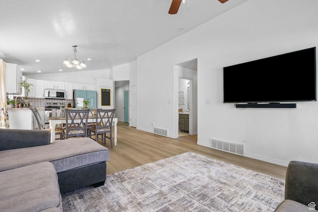 living room featuring lofted ceiling, ceiling fan, light wood-style flooring, a chandelier, and baseboards