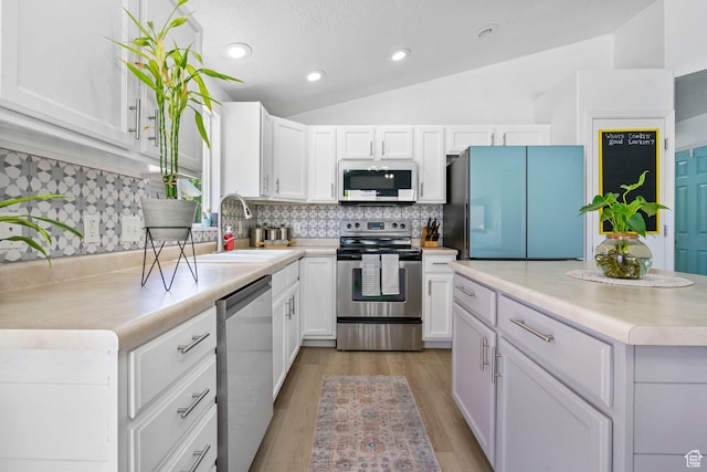 kitchen featuring appliances with stainless steel finishes, a sink, white cabinetry, light countertops, and backsplash