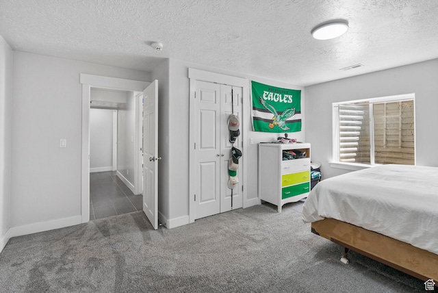 carpeted bedroom with a textured ceiling, baseboards, and a closet