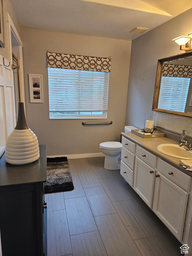 bathroom featuring tasteful backsplash, toilet, vanity, wood finished floors, and baseboards