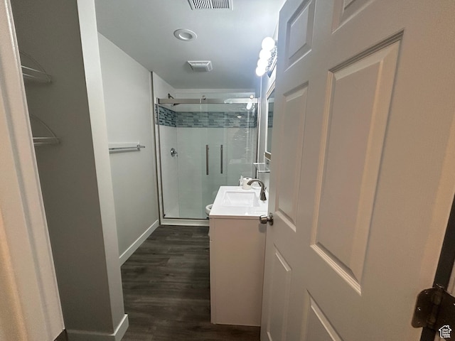 bathroom featuring a shower stall, vanity, wood finished floors, baseboards, and toilet