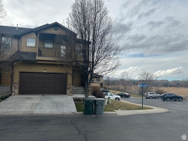 view of front of property with stucco siding, stone siding, an attached garage, and driveway