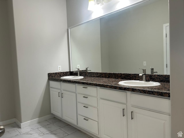 bathroom with marble look tiles, double vanity, and baseboards