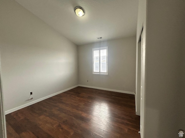 empty room with lofted ceiling, dark wood-type flooring, and baseboards
