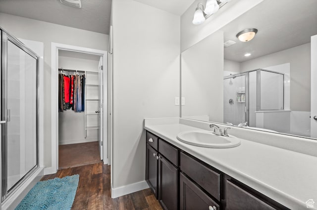 6616 W 7735 S, West Jordan, UT 84081 - bathroom featuring wood finished floors, a shower stall, baseboards, a walk in closet, and vanity