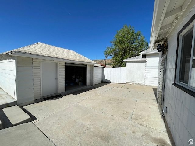 view of patio with an outbuilding, a detached garage, and fence