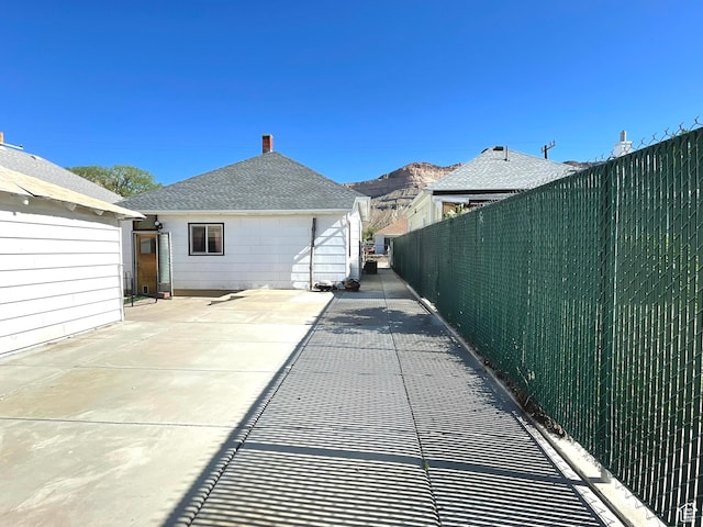 rear view of property featuring fence, a patio area, and a shingled roof