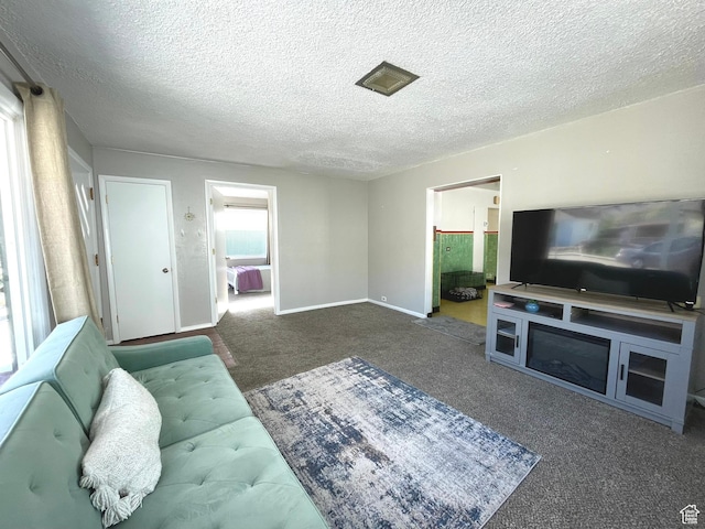 carpeted living area with a textured ceiling and baseboards