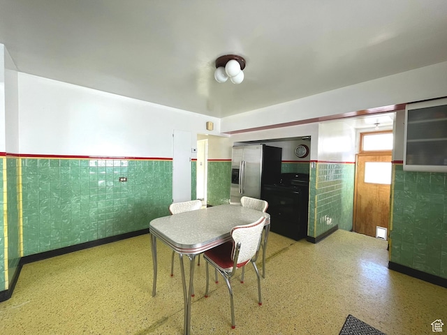 dining area with a wainscoted wall and tile walls