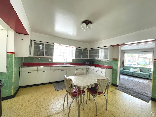 kitchen with a sink, stainless steel countertops, healthy amount of natural light, and white cabinets